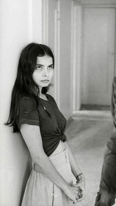 black and white photograph of a woman leaning against a wall with her hands on her hips