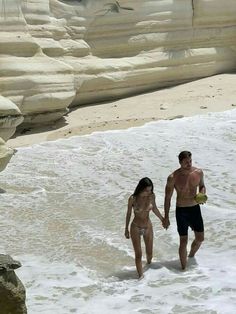 a man and woman walking in the ocean