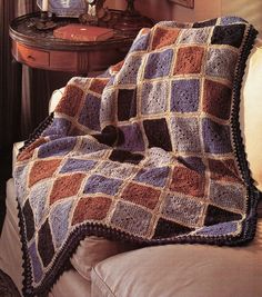 a crocheted afghan sits on a couch next to a table with a mirror