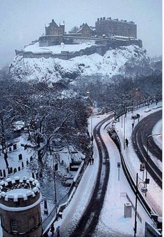 a snow covered road with a castle in the background