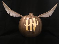 a pumpkin with wings and the letter h painted on it's side, sitting in front of a black background