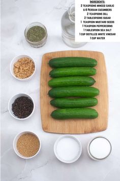 cucumbers and spices on a cutting board with ingredients for the recipe in bowls