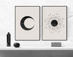 two black and white art prints on a wall next to a vase with a bottle