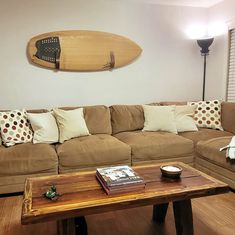 a living room with a couch, coffee table and surfboard on the wall above it