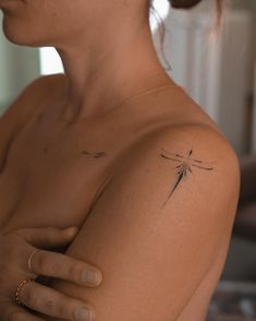 a woman with a dragonfly tattoo on her left shoulder and right arm is looking at the camera