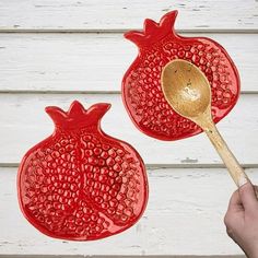 two red glass pomegranates with a wooden spoon