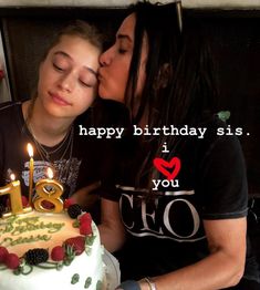 two people sitting next to each other in front of a cake with candles on it