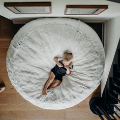 a little boy laying in a bean bag chair on top of a wooden floor next to stairs