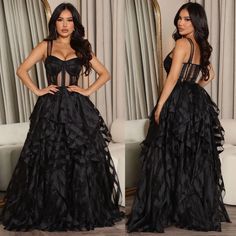 the woman is wearing a black dress with ruffled skirt and straps on her waist