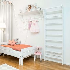 a bedroom with white walls and wooden flooring is decorated in pastel pink tones