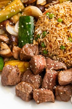 a white plate topped with meat and veggies covered in sesame seed rice next to broccoli