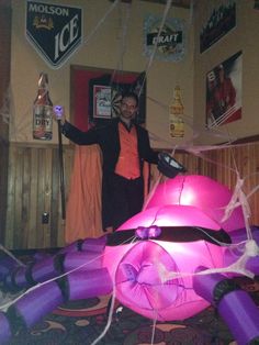 a man standing next to an inflatable pink ballon with spider webs on it