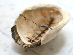 an empty wooden bowl on a marble countertop with barbed wire in the bottom half