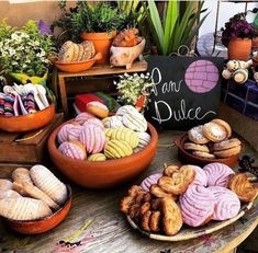 a table topped with lots of different types of pastries on plates next to potted plants