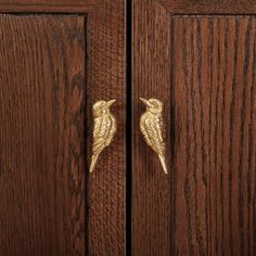 two golden birds are on the handles of wooden doors