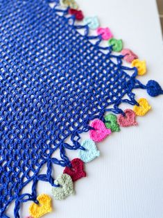 a crocheted table cloth with multicolored hearts on it