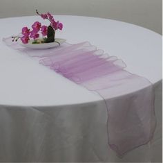 a white table topped with a bowl of pink flowers and a purple organ - streamer