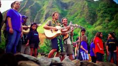 a group of people standing next to each other on top of a lush green hillside