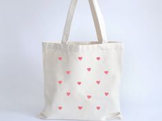 This lightweight eco friendly pink heart canvas cotton tote bag is the perfect every day accessory. Whether you are using it to run errands or just carrying around everyday essentials, this cute minimalist tote is cute all year long.  The bag features 20" handles (made from the same canvas), making it easy to carry even with a week's worth of shopping. Printing options for two sides. Every item is custom produced, made to order, so please note each item is unique and may differ in color slightly Coquette Tote Bag, Minimalist Tote Bag, Heart Tote Bag, Minimalist Tote, Heart Canvas, Canvas Making, Eco Conscious, Everyday Essentials, Tote Bag Design