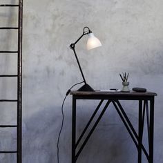 a table with a lamp on it next to a ladder and a light bulb in the corner