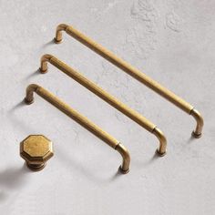 four brass handles and knobs on a white surface, one has a hexagonal hole in the middle