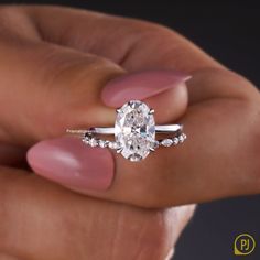 a woman's hand holding an oval diamond ring