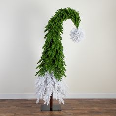 there is a fake christmas tree on the floor in front of a white wall and wooden floor