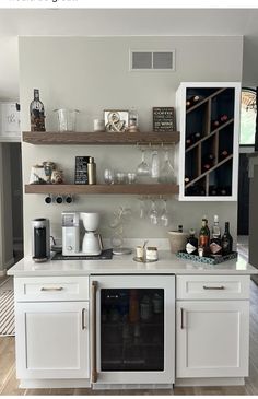 a kitchen with white cabinets and shelves filled with wine glasses, bottles and other items