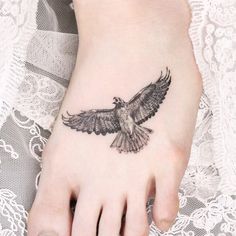 a bird tattoo on the foot of a woman