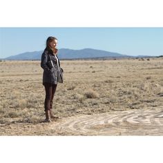 a woman standing in the middle of an open field