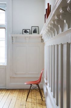 a red chair sitting on top of a hard wood floor next to a white wall