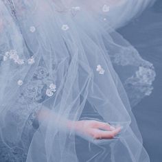 a woman wearing a veil and holding her hand out to the side with flowers on it