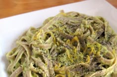 a white plate topped with pasta covered in pesto