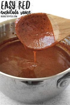 a wooden spoon is being used to stir sauce in a pot with the words easy red enchilada sauce on it