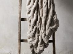 a large white blanket hanging from a wooden ladder