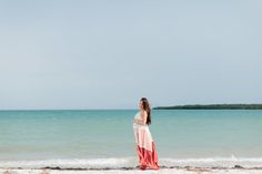 a woman standing on top of a beach next to the ocean