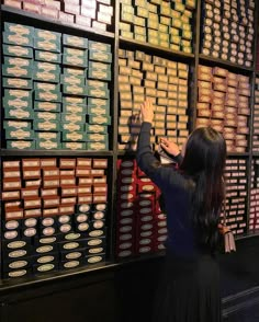 a woman standing in front of a wall filled with lots of different types of boxes