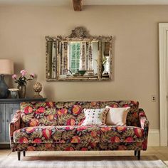 a living room filled with furniture and a mirror on the wall above it's headboard