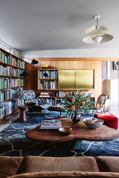 a living room filled with lots of books on top of a wooden table next to a couch