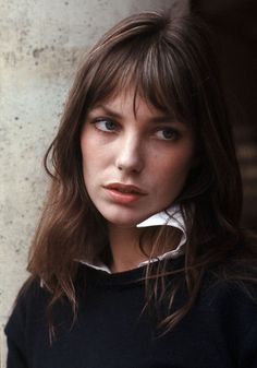 a black and white photo of a woman with long hair wearing a sweater looking at the camera