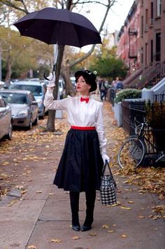 a woman holding an umbrella while standing on a sidewalk