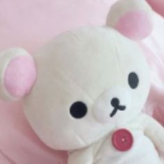 a white teddy bear sitting on top of a pink blanket with buttons in its paws