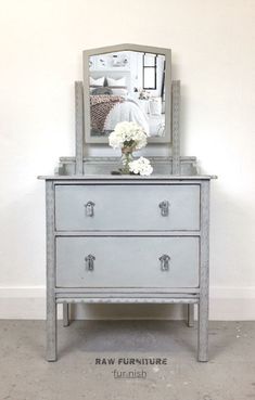 a dresser with flowers and a mirror on top