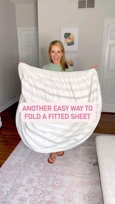 a woman holding up a white sheet with the words another easy way to fold a fitted sheet