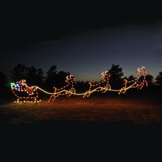 a lighted sleigh with santa claus on it in the middle of a field