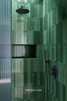 a green tiled bathroom with shower head and handset