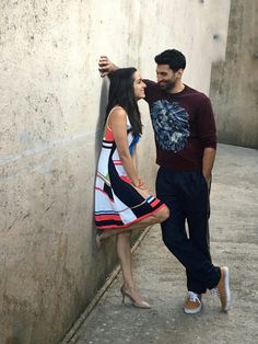 a man and woman leaning against a wall