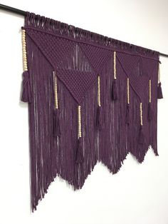 a purple wall hanging with tassels on it