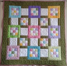 a quilted wall hanging on the side of a building with colorful squares in it