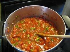 a pot filled with lots of food sitting on top of a stove next to a wooden spoon